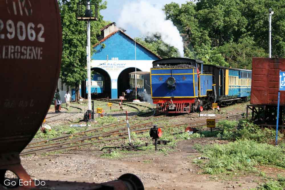 X Class steam locomotive built at Swiss Locomotive and Machine Works of Winterthur in Switzerland passes an engineering shed on the Nilgiri Mountain Railway in southern India