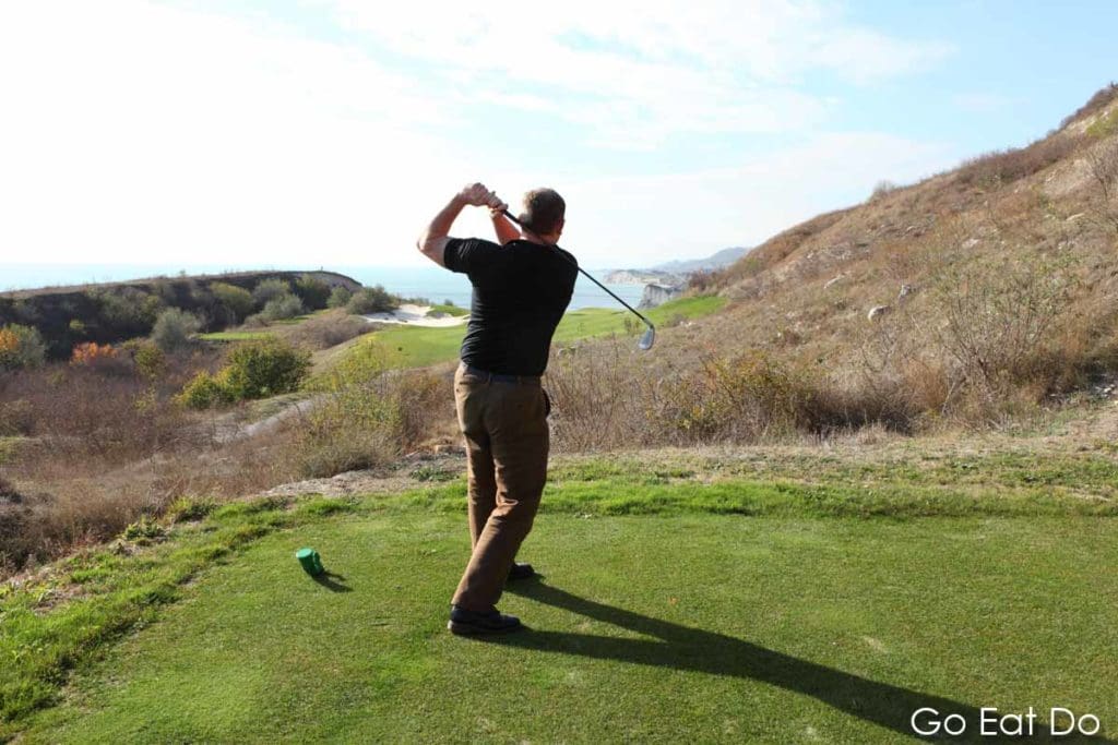 Man teeing off on the 18-hole golf course at Thracian Cliffs Golf * Beach Resort in Bulgaria.