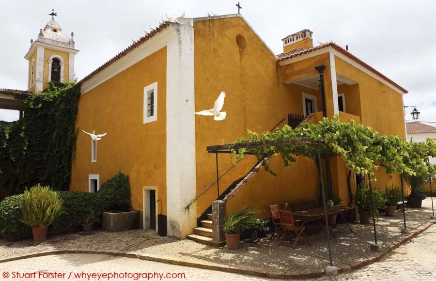 White doves fly around the chapel at the Quinta de Sant'Ana in the village of Gradil, near to Mafra in Portugal