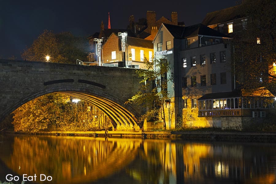 The River Wear flows by the Framwellgate Bridge illuminated at night in Durham, England