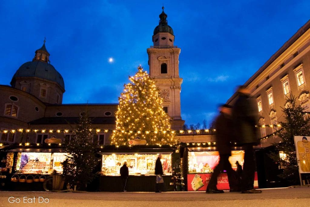 A Christmas tree and stalls at the Salzburger Christkindlmarkt at dusk.