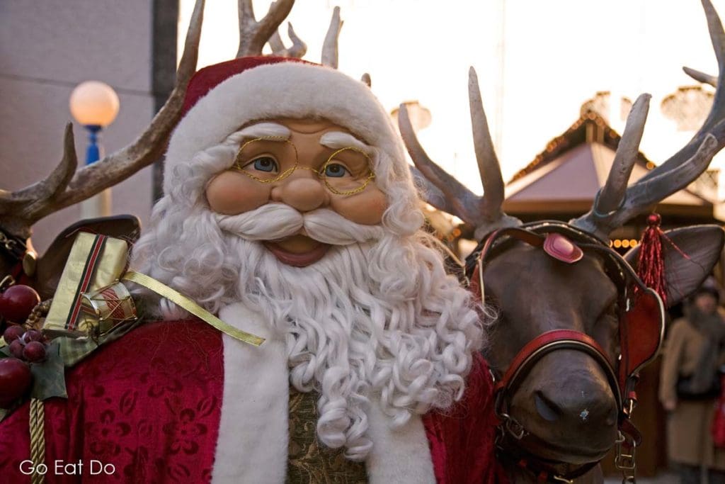 Santa Claus by a reindeer at a Christmas market in Munich, Germany.