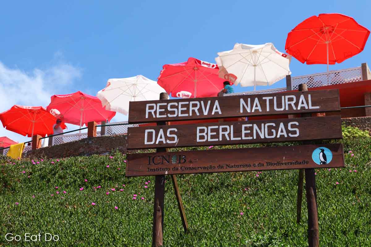 Red and white sunshades on the Berlengas Islands and a sign for the Reserva Natural das Berlengas nature reserve