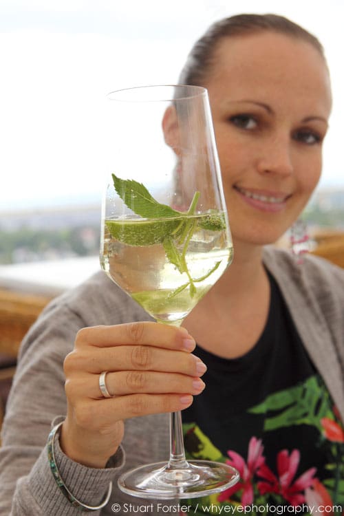 A smiling woman enjoys a Hugo cocktail in Wiesbaden, Germany