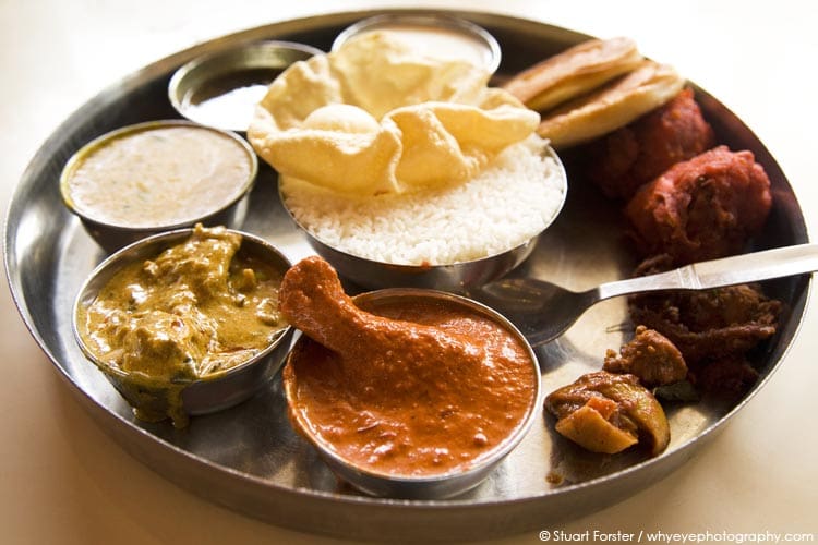 Traditional Indian thali lunch chicken tikka, pickles, curry varieties, dal, rasam, curd, boiled rice, coin parathas and a mini poppadum served in India