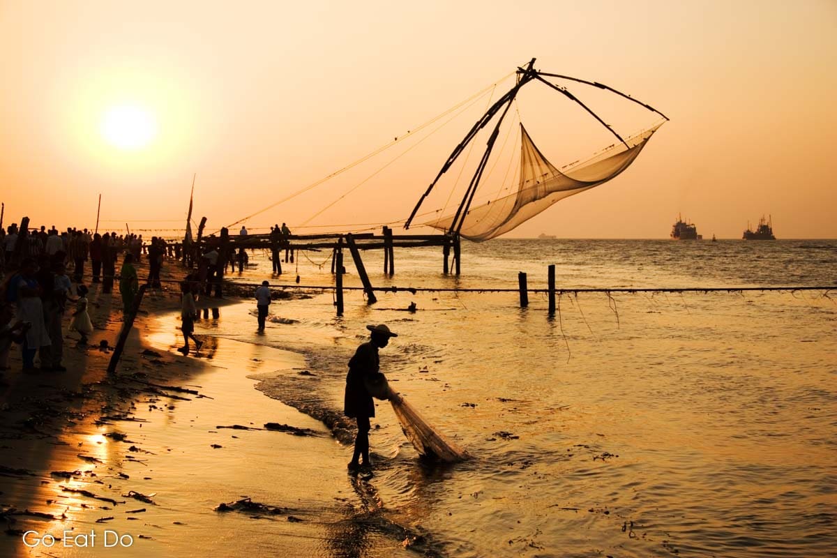 A fisherman silhouetted during sunset by a Chinese fishing net in Kerala, India.