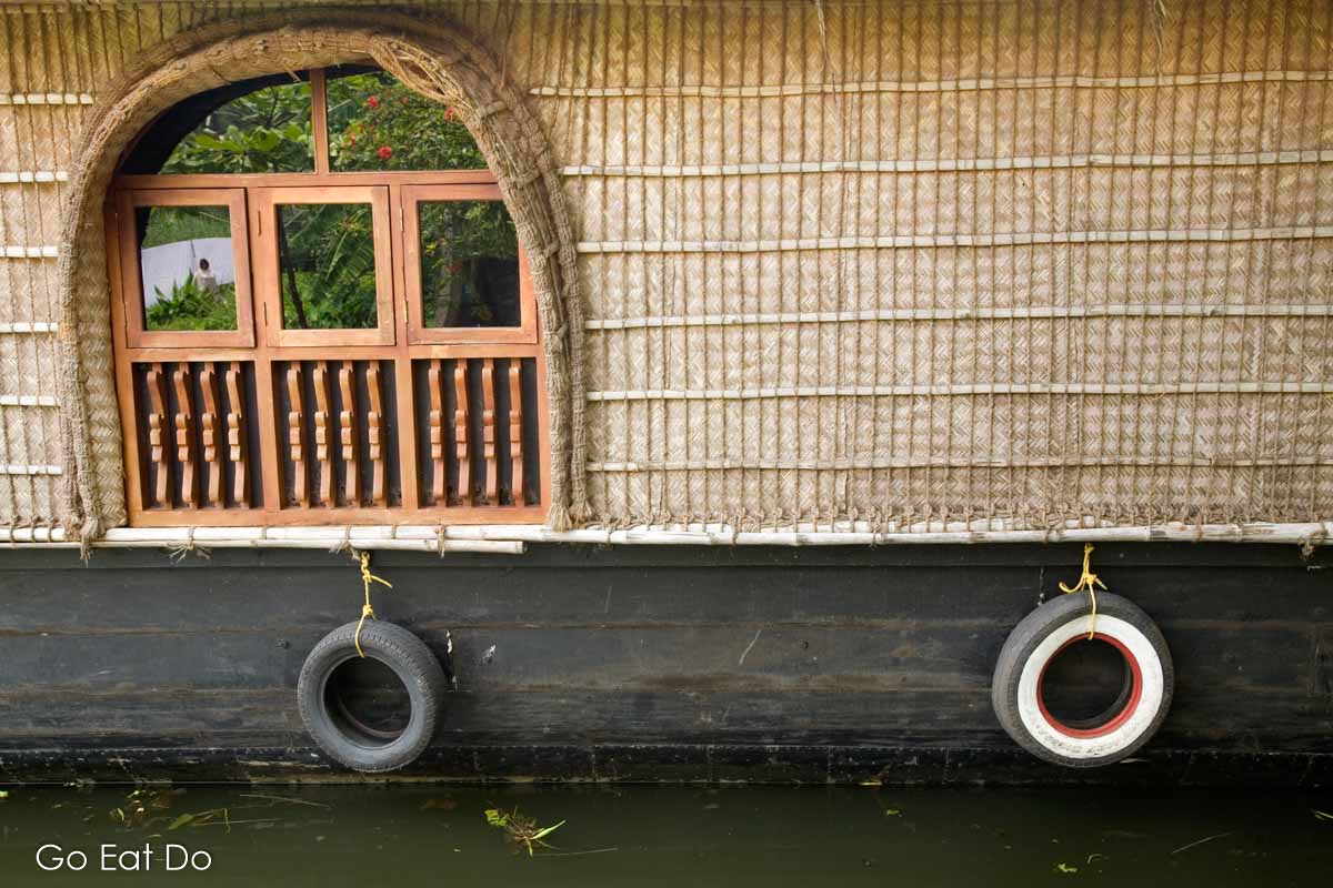 A Kerala houseboat with a thatched roof and window.
