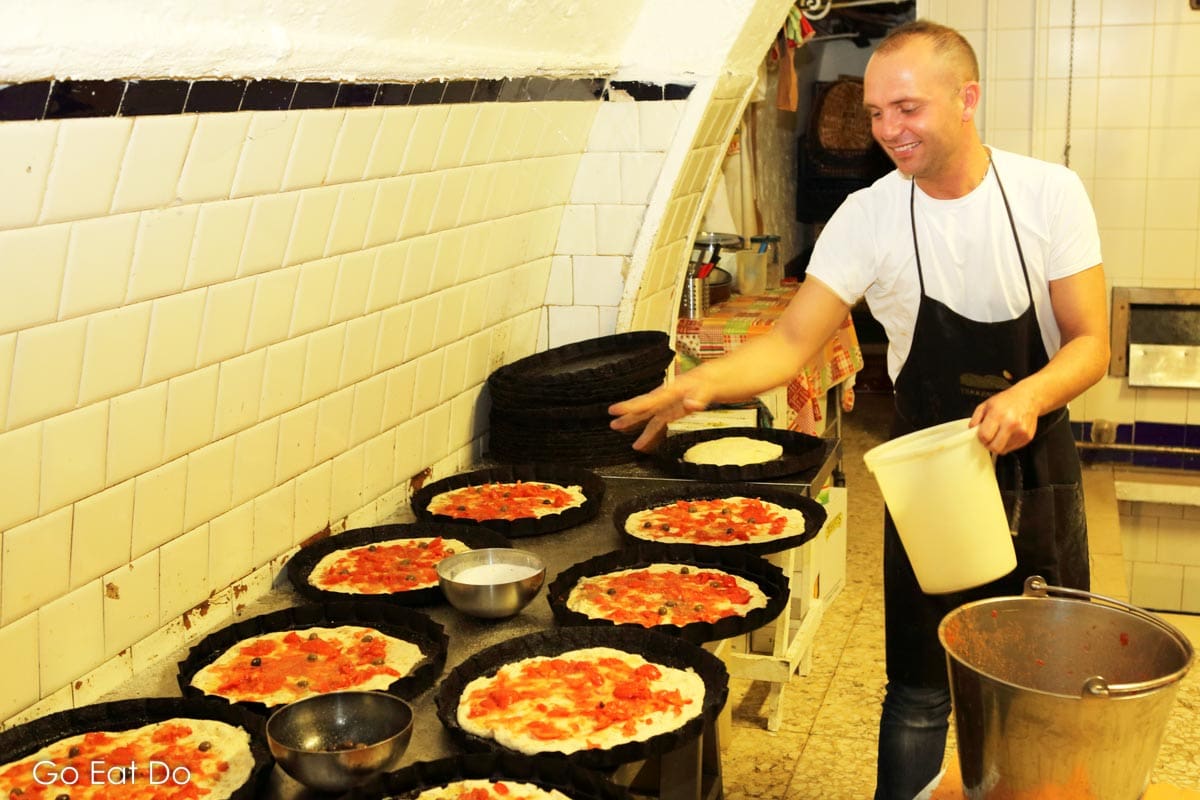 Baker baking focaccia at the Panificio Fiore bakery, one of the stops during Veloservice’s Bari food tour by rickshaw.