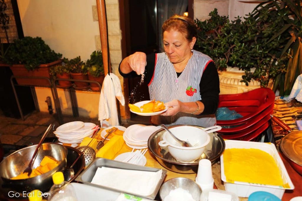 Carmela, a local woman, prepares sgagliozze, polenta fritters, a traditional Puglian dish, on a square in Bari, Italy.
