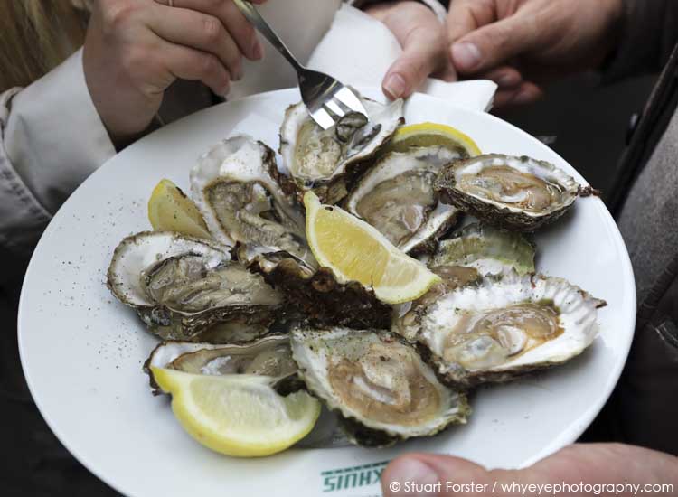 People eat from a plate of oysters at the Brasserie Pakhuis oyster festival in Ghent, Belgium.