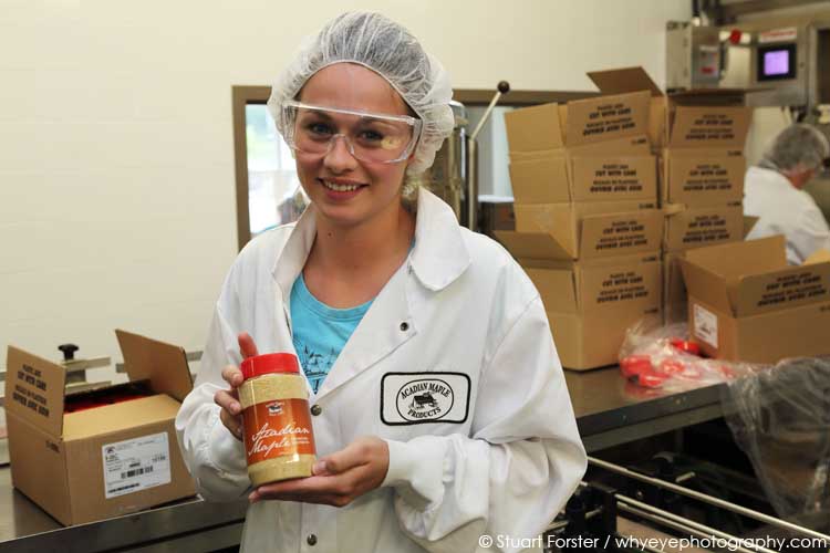 A pretty woman shows off maple sugar straight off the production line at Acadian Maple Products in Nova Scotia, Canada