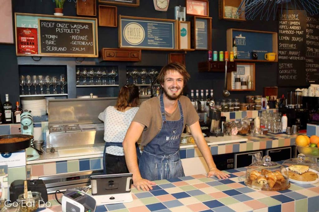 A smiling member of staff at the counter of the Wasbar cafe and wash salon in Ghent, Belgium