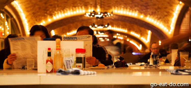 People reading the Grand Central Oyster Bar menu in New York City's Grand Central Terminal.