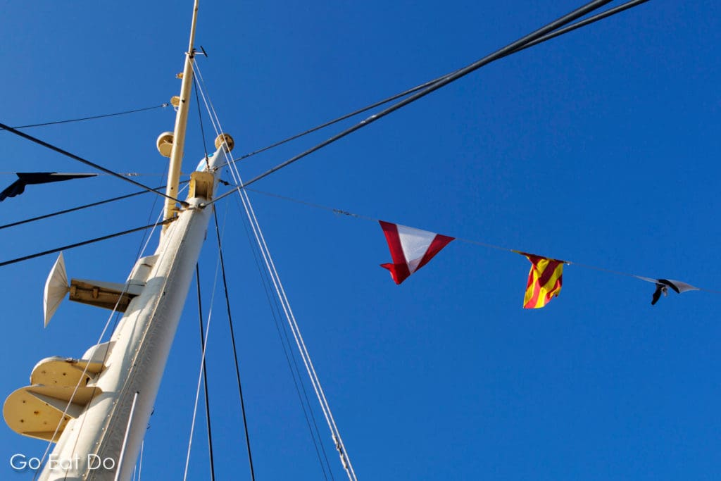 Flags flying from the mast of the Royal Yacht Britannia on a sunny day in Edinburgh, Scotland
