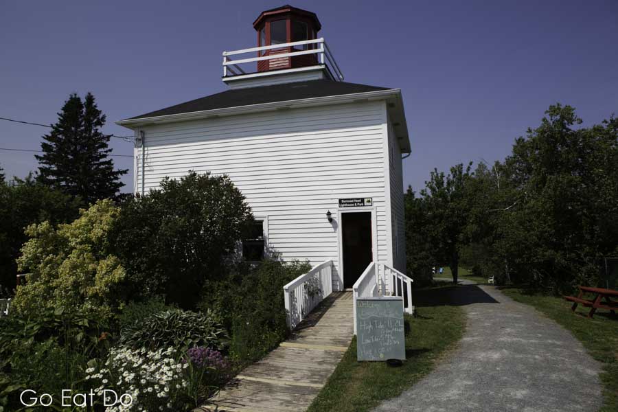 Historic white wood lighthouse under blue sky at Burntcoat Head in Nova Scotia, Canada