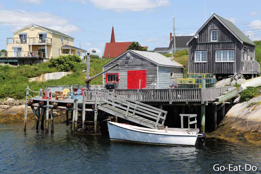 Boat in the water by waterfront huts and houses at Peggy's Cove in Nova Scotia, Canada