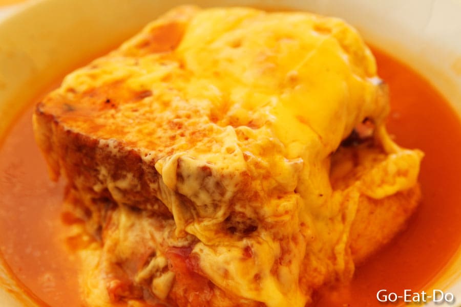 Close-up view of a cheese-covered francesinha sandwich, a local delicacy in Porto, Portugal