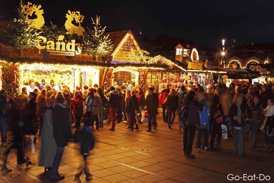 People visit illuminated stalls at the Christmas Market (Weihnachtsmarkt) in Stuttgart, Germany