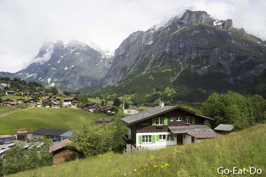 Alpine landscape featuring Swiss chalets, mountains and grassy meadows near Interlaken, Switzerland