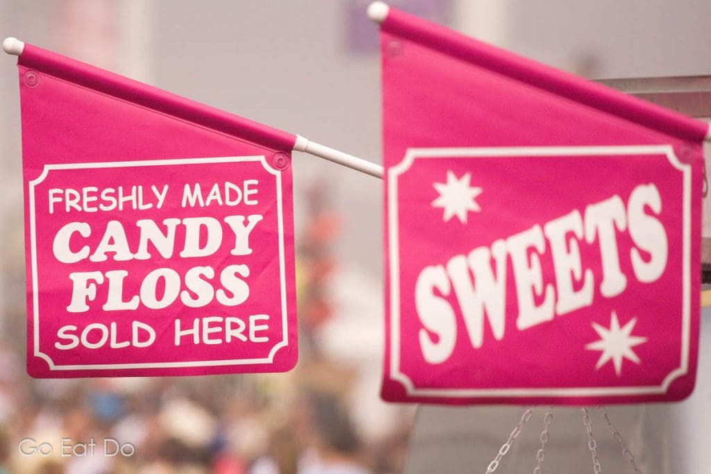 Flags advertise candy floss and sweets sold from trucks parked at the seaside.