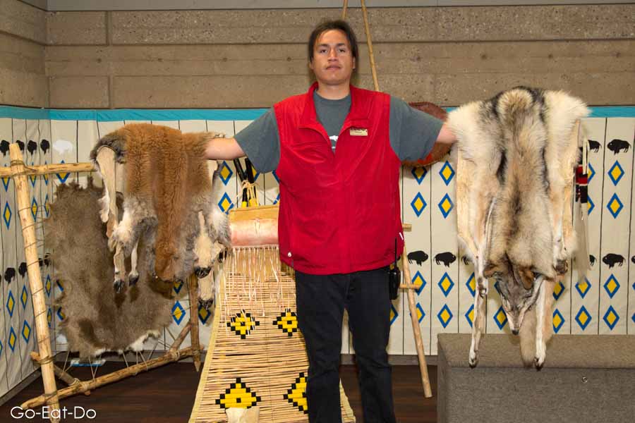 First Nations' guide showing artefacts made from bison at Head-Smashed-In Buffalo Jump UNESCO World Heritage Site in Alberta, Canada