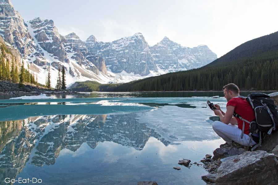 Man setting up photography gear at Moraine Lake in the Canadian Rockies at Banff National Park in Alberta, Canada