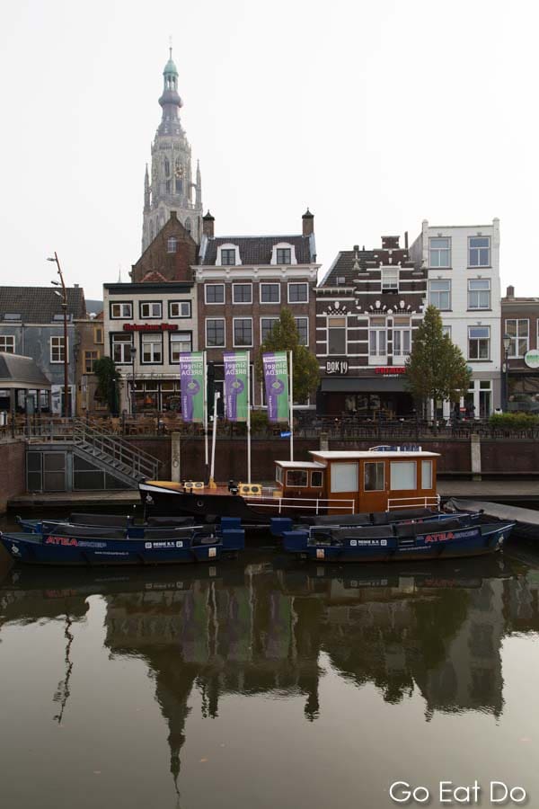 Grote Kerk or Onze-Lieve-Vrouwekerk (Church of Our Lady) dominates the skyline above a boat docked at the Nieuwe Mark in Breda, the Netherlands