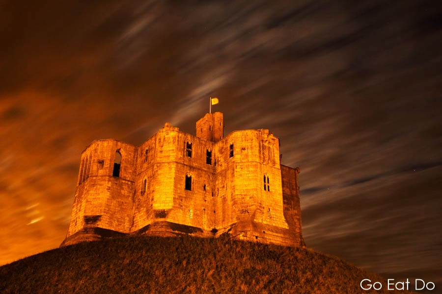 Clouds scud past Warkworth Castle at night in Northumberland, England