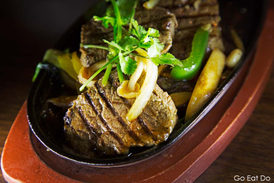 Grilled fillet beef with pan-fried vegetables and topped with coriander and served on a sizzling platter in Ramside Hall's Fusion restaurant in Durham, England