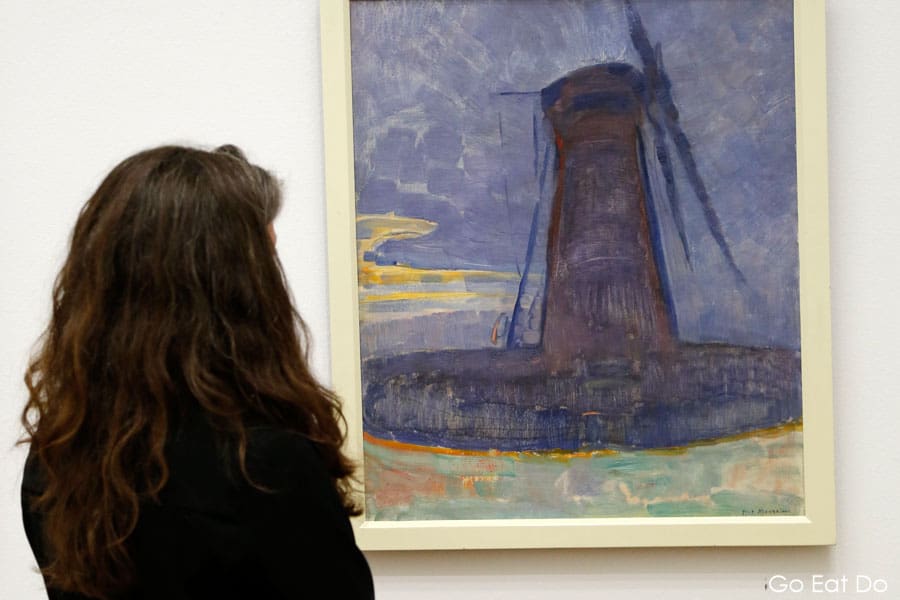 A woman admires a painting by Piet Mondrian.