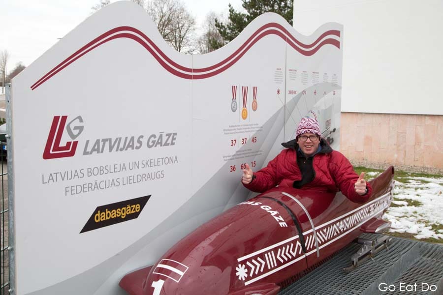 Travel blogger Stuart Forster sitting in a bobsleigh at Sigulda Bobsleigh and Luge Track in Latvia