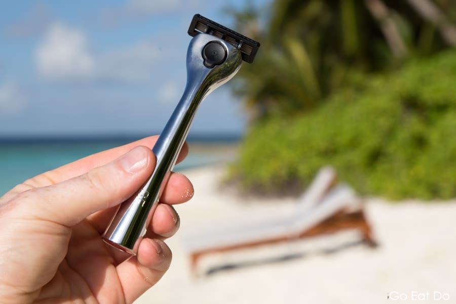 Man holds a Cornerstone razor on a white sand beach in the Maldives
