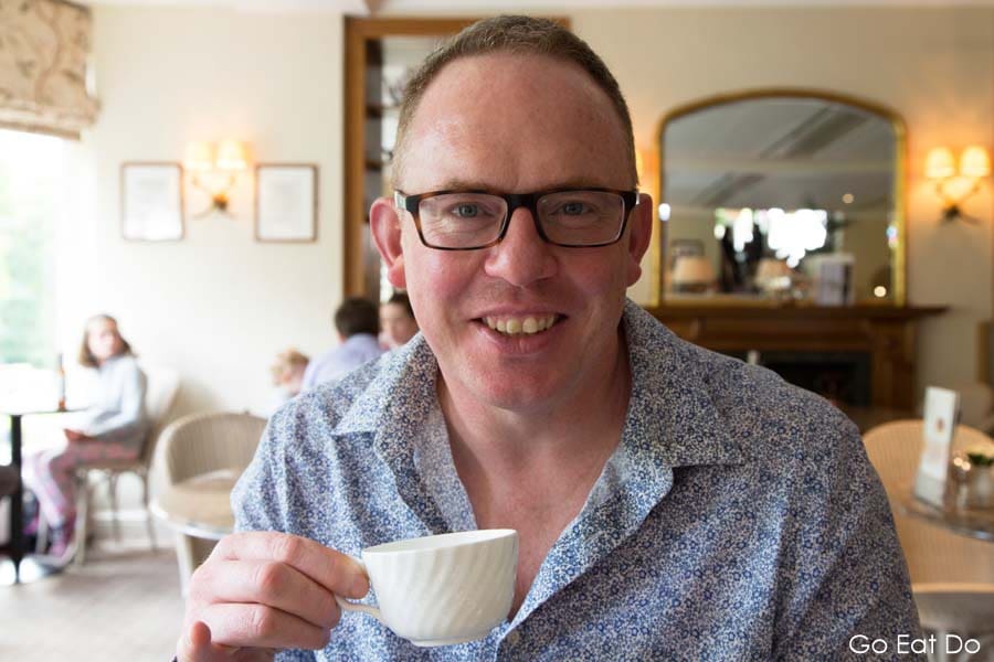 Travel and food writer Stuart Forster smiling with a cup of tea at Bettys Cafe Tea Rooms in Harrogate, North Yorkshire, England