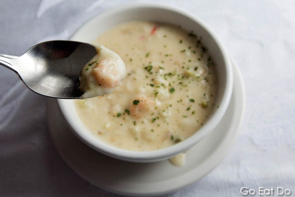 Spoon dips into bowl of seafood chowder served at Skipper Ben's at Cupids in Newfoundland and Labrador, Canada