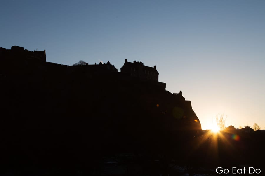 Edinburgh Castle and Castle Rock silhouetted against the sun.