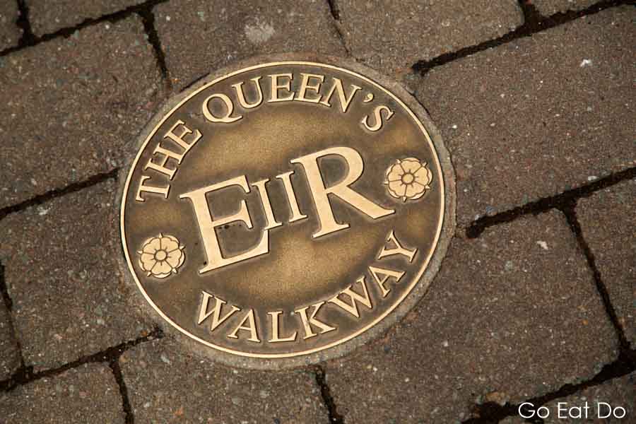Brass sign on pavement marking the Queen's Walkway in Windsor, England,