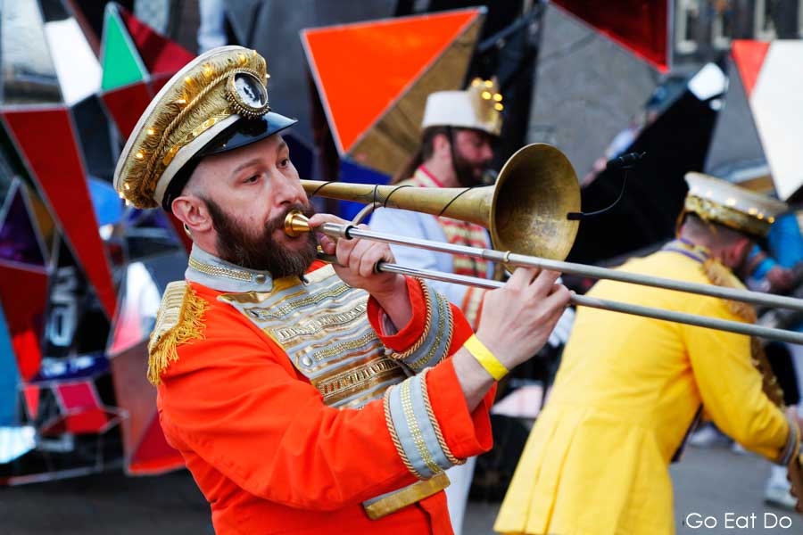 Musicians playing trombone in a colorful costume on Newcastle Quayside during Great Exhibition of the North opening ceremony