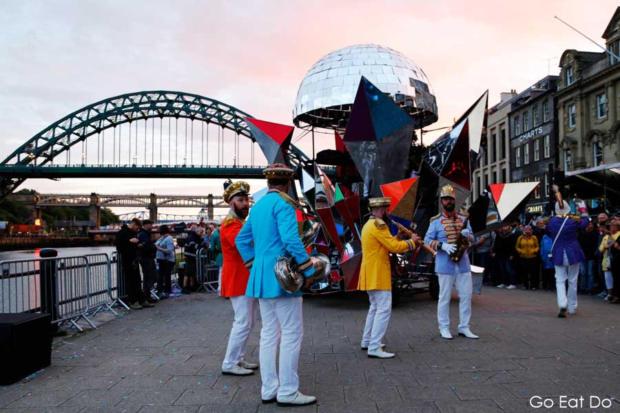 Colourful musicians in band playing under Tyne Bridge on Newcastle Quayside during Great Exhibition of the North opening ceremony
