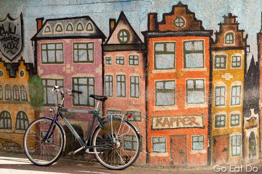 Bicycle leaning against an urban wall decorated with street art depicting Dutch houses in Leeuwarden, the Netherlands