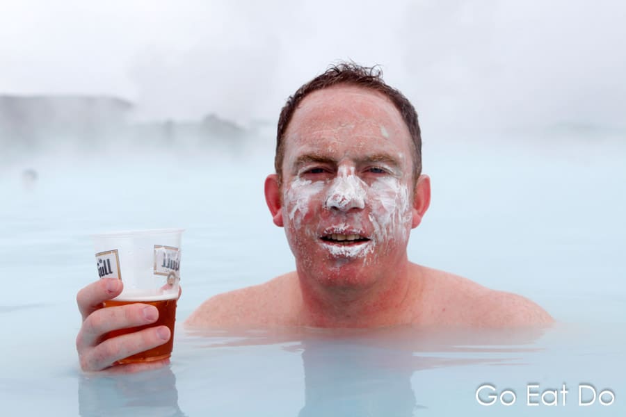 Travel blogger Stuart Forster relaxing with a cold beer and mud mask on his face in the heated pool of the Blue Lagoon in Iceland