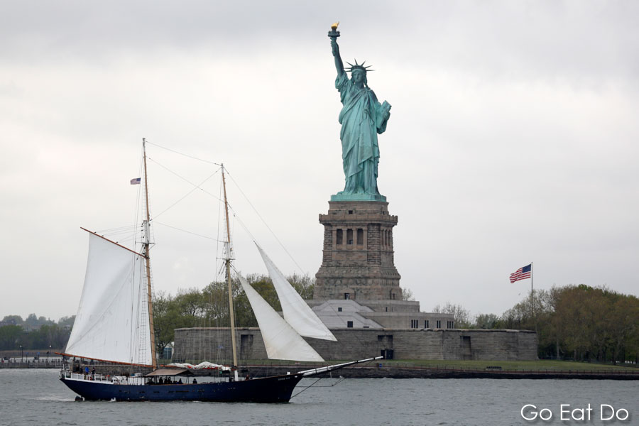 A yacht sails by the Statue of Liberty in New York City's harbour in the USA