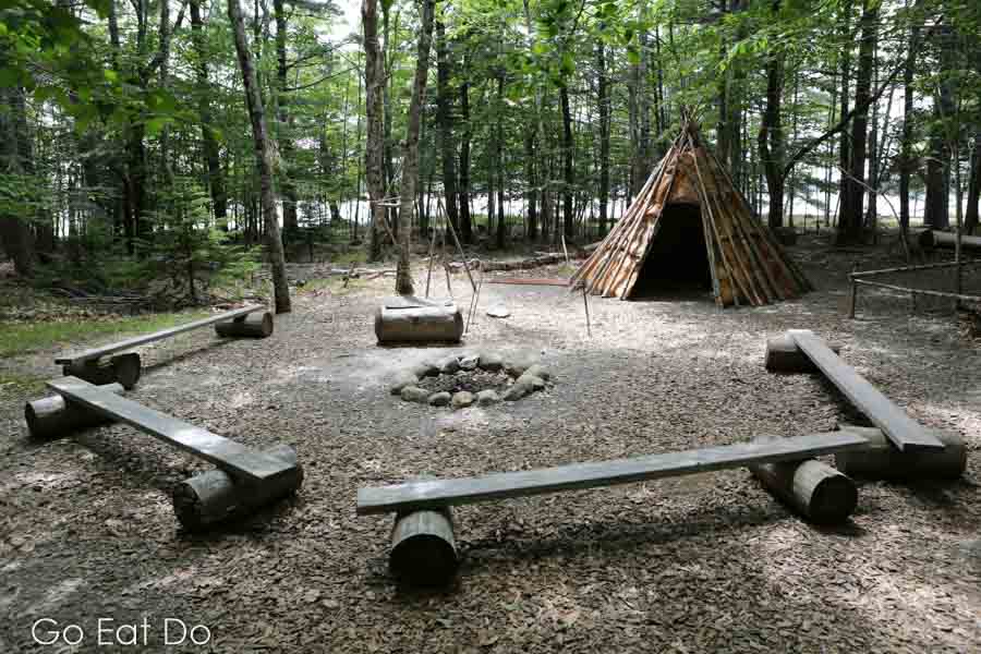 A birch bark tipi in Keji and seating round a fire pit.
