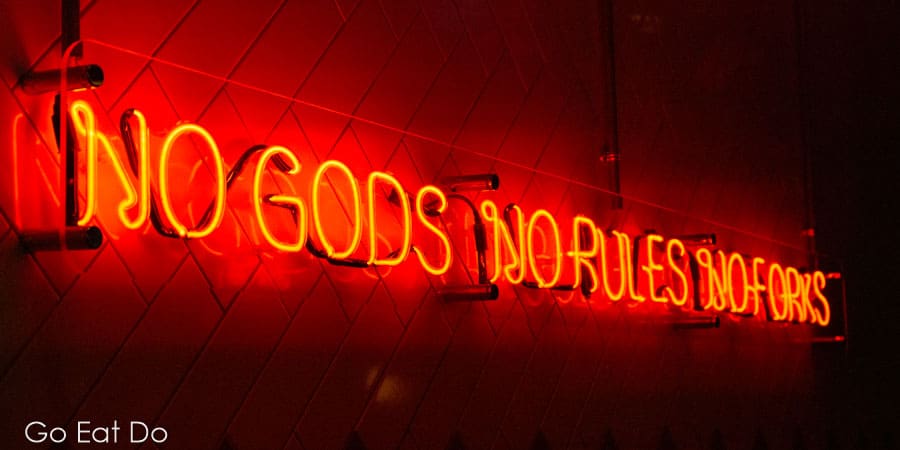 Saying it in a capital way, a neon light says 'No Gods, No Rules, No Forks' at the Pizza Punk Newcastle restaurant.