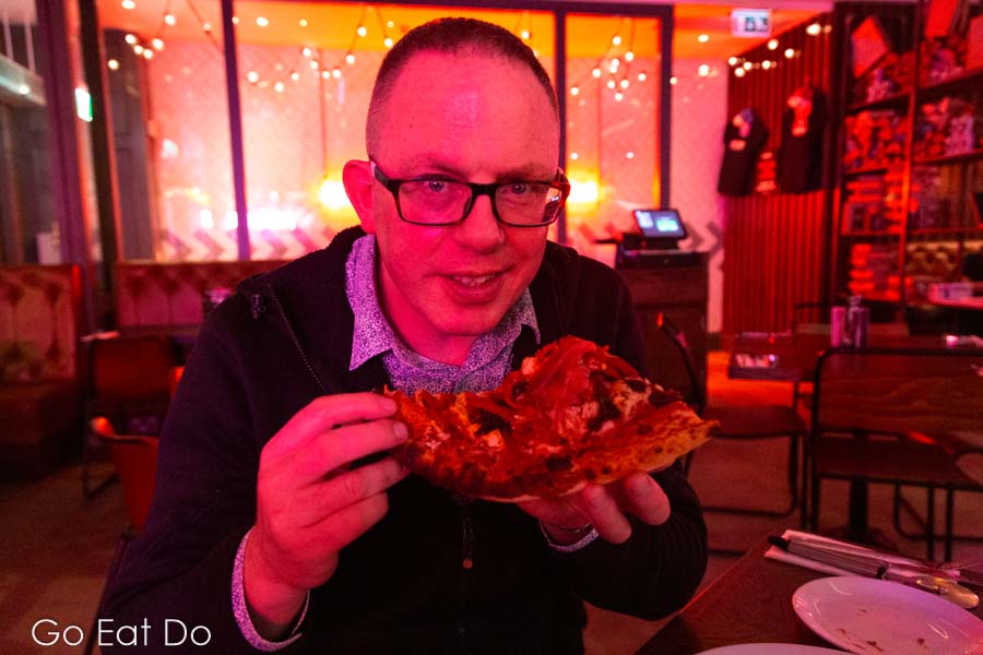 Travel and food blogger Stuart Forster eating a slice of pizza at the Pizza Punks Newcastle restaurant.