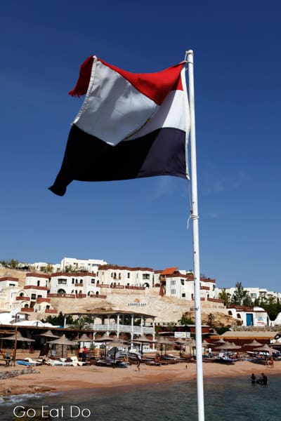 The Egyptian national flag flutters in the clear blue sky by the Red Sea at Sharm el Sheikh.