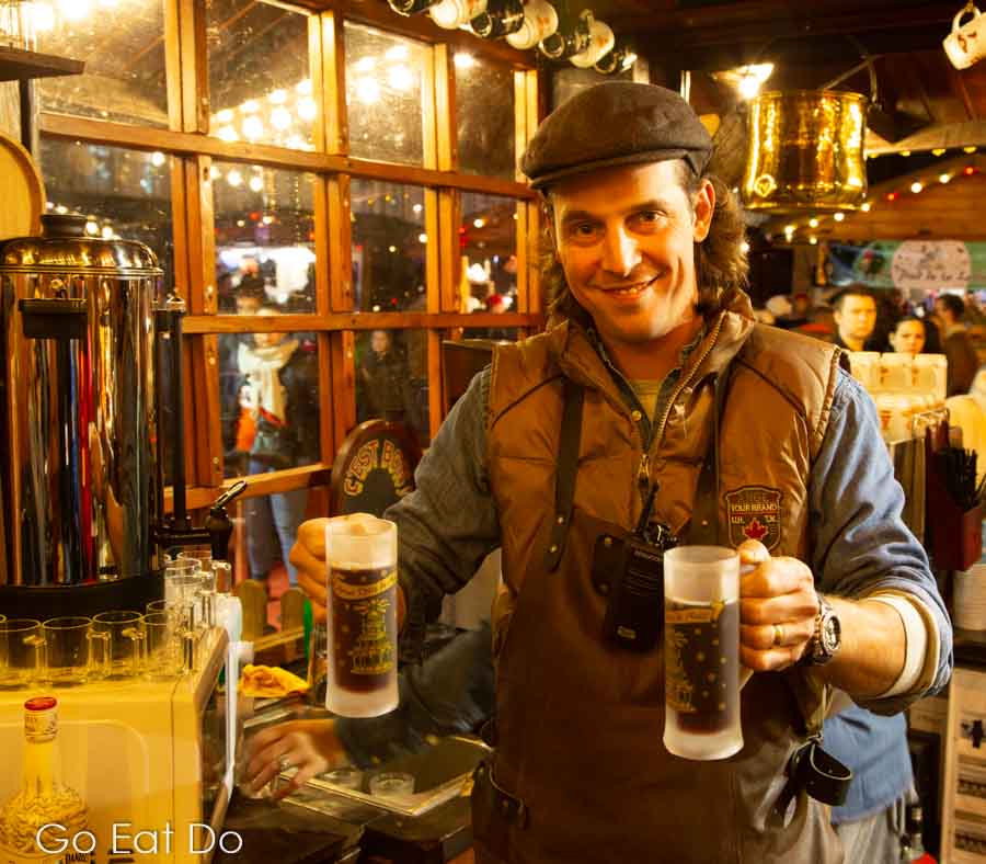 Man smiles and serves drinks at Doctor Steam Bar at Arras Christmas market in northern France