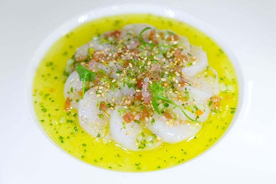Carpaccio of scallop served in a tangy sauce featuring lime juice and olive oil.