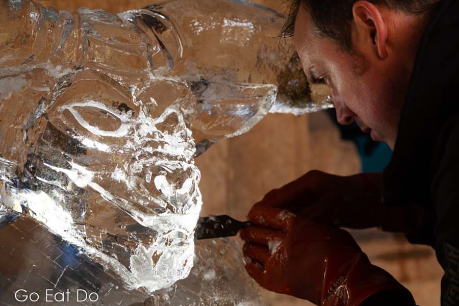Matt Chaloner concentrating while sculpting the face of a minotaur in a block of ice at Durham's Fire and Ice festival