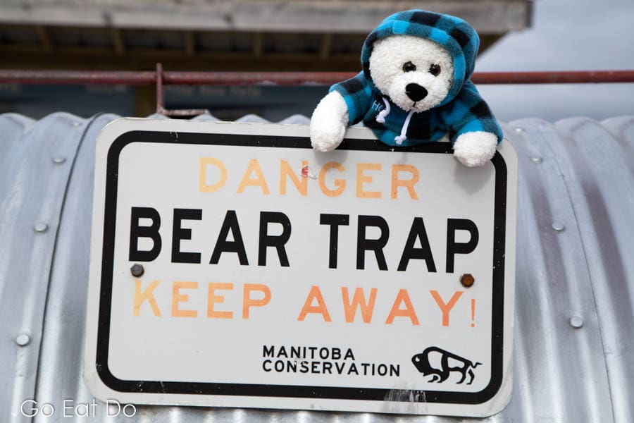 A teddy bear by Manitoba Conservation sign warning of the danger posed by a bear trap at the Polar Bear Holding Facility at Churchill.