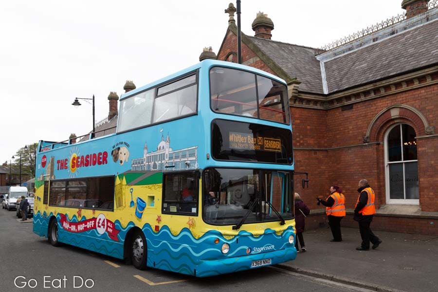 Seasider open-topped bus picking up passengers outside of Tynemouth Metro station in North East England